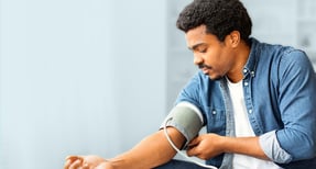 Employee checking blood pressure with home monitor to manage health and rising healthcare costs.