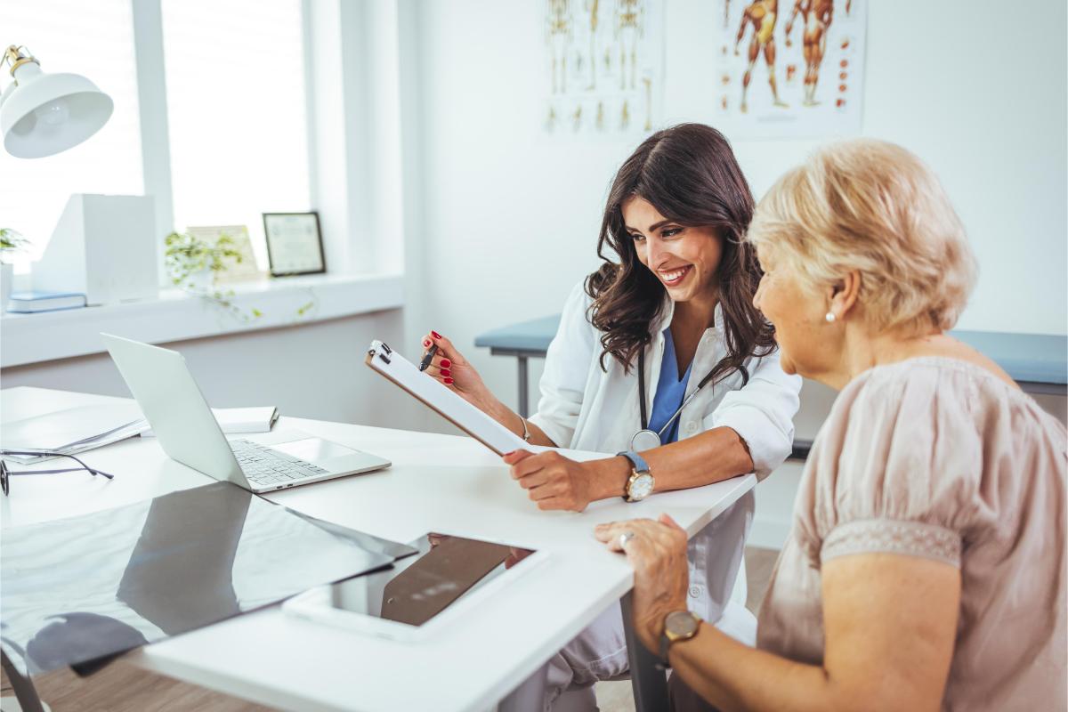 Female doctor explaining diagnosis to her patient. A smiling mid adult female doctor listens as a female patient discusses her health. Caring doctor listens to patient